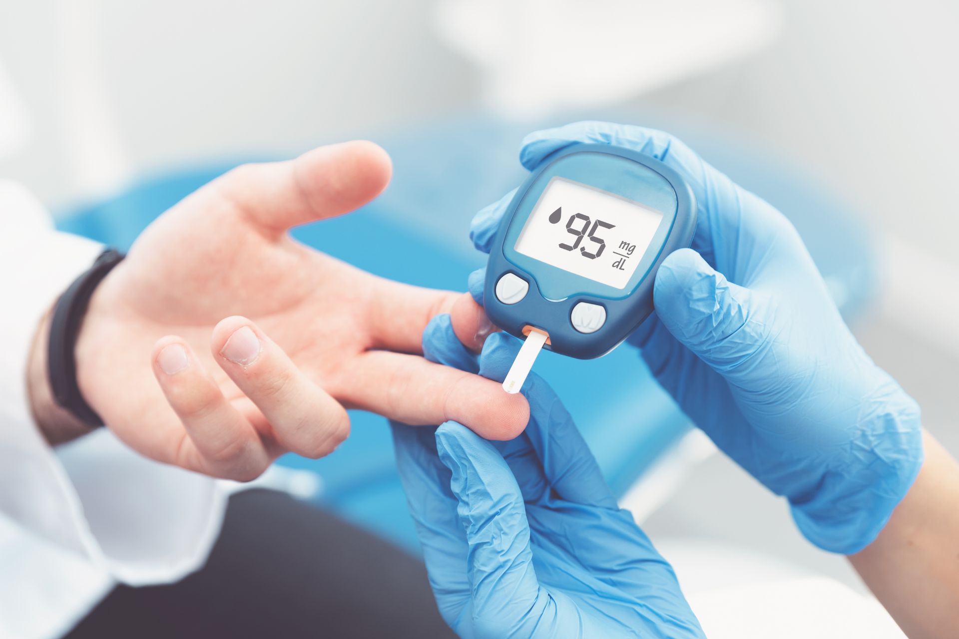 Healthcare worker testing a patient's blood sugar level with a glucose meter.
