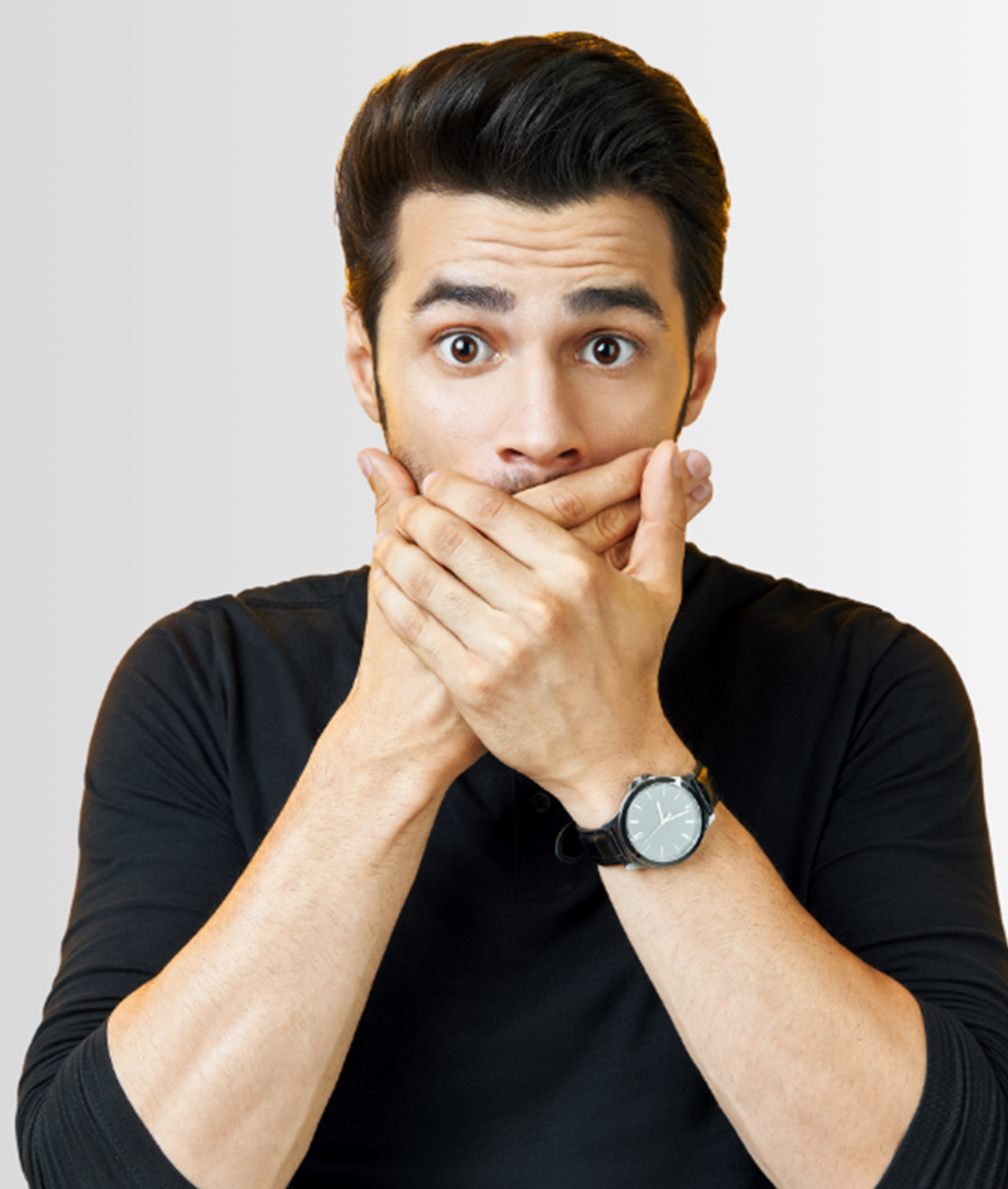 Surprised young man covering his mouth with both hands against a neutral background, expressing shock or concern.