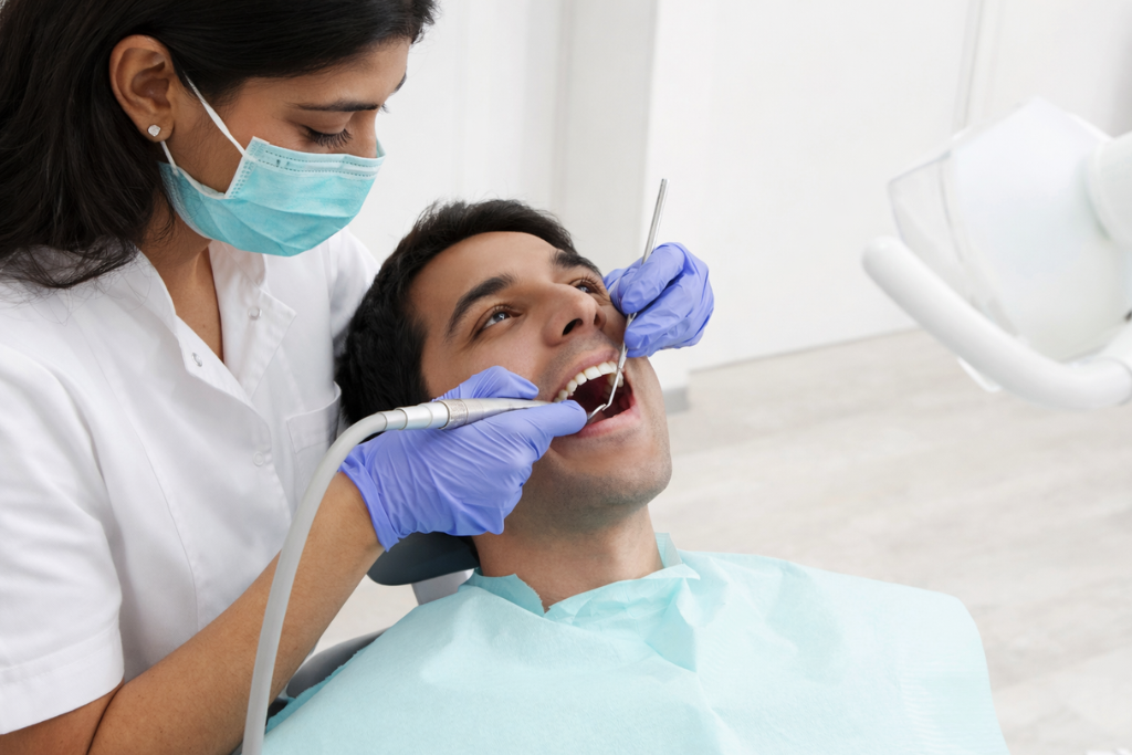 Dentist performing dental scaling procedure on a patient in a modern dental clinic treatment room.
